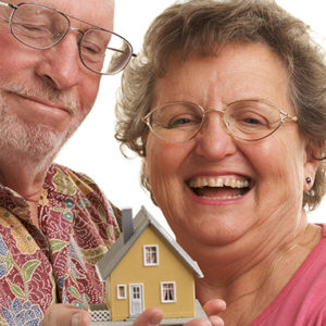Mature Couple holding a miniature model of a home modification house