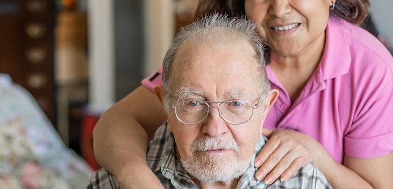 Caregiver with hands on older man's shoulders