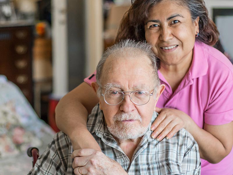 Caregiver with hands on older man's shoulders